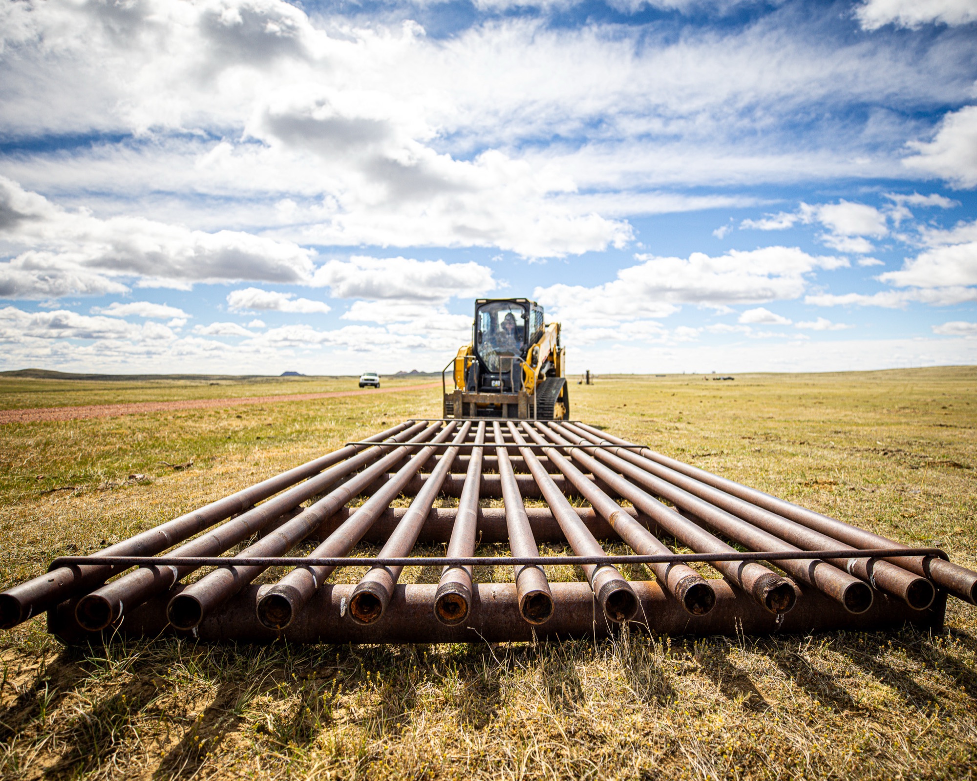 Cattle guard pipe rails laid out with CAT skid steer on Wyoming rangeland