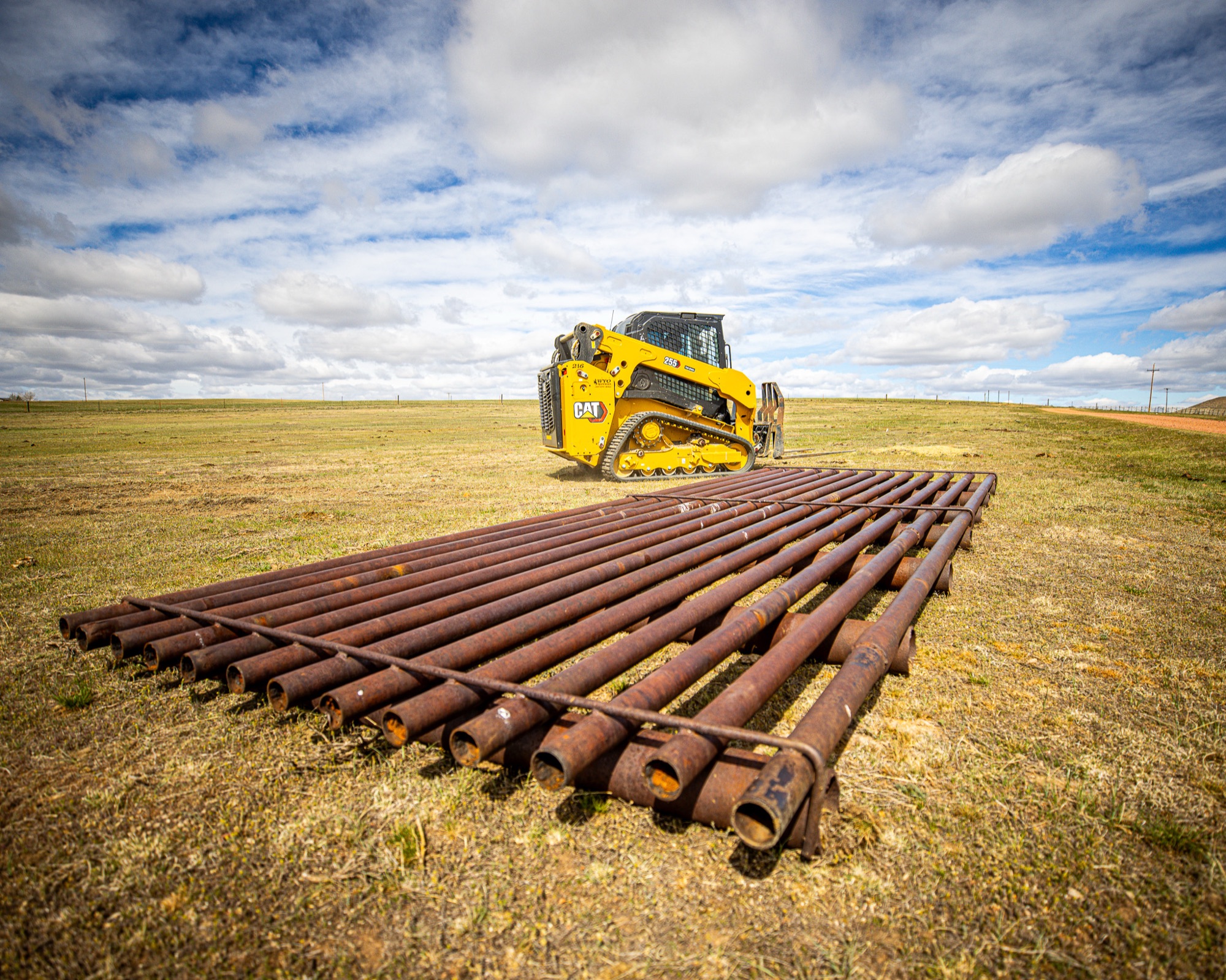 Fabricated cattle guard pipe rails with CAT skid steer ready for installation
