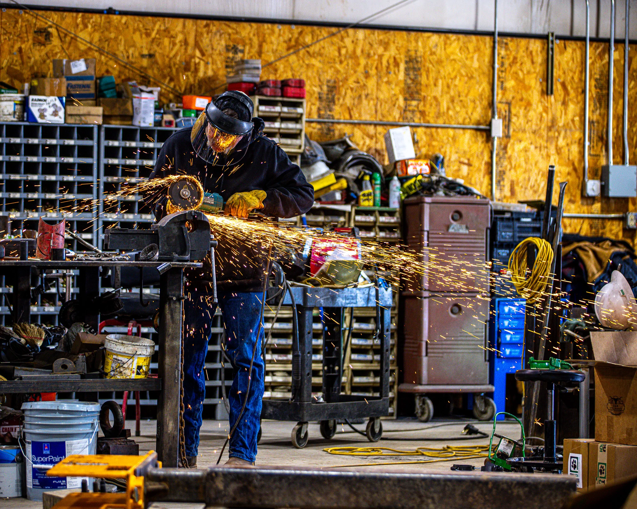 WYO Services fabrication shop with crew member grinding steel at workbench