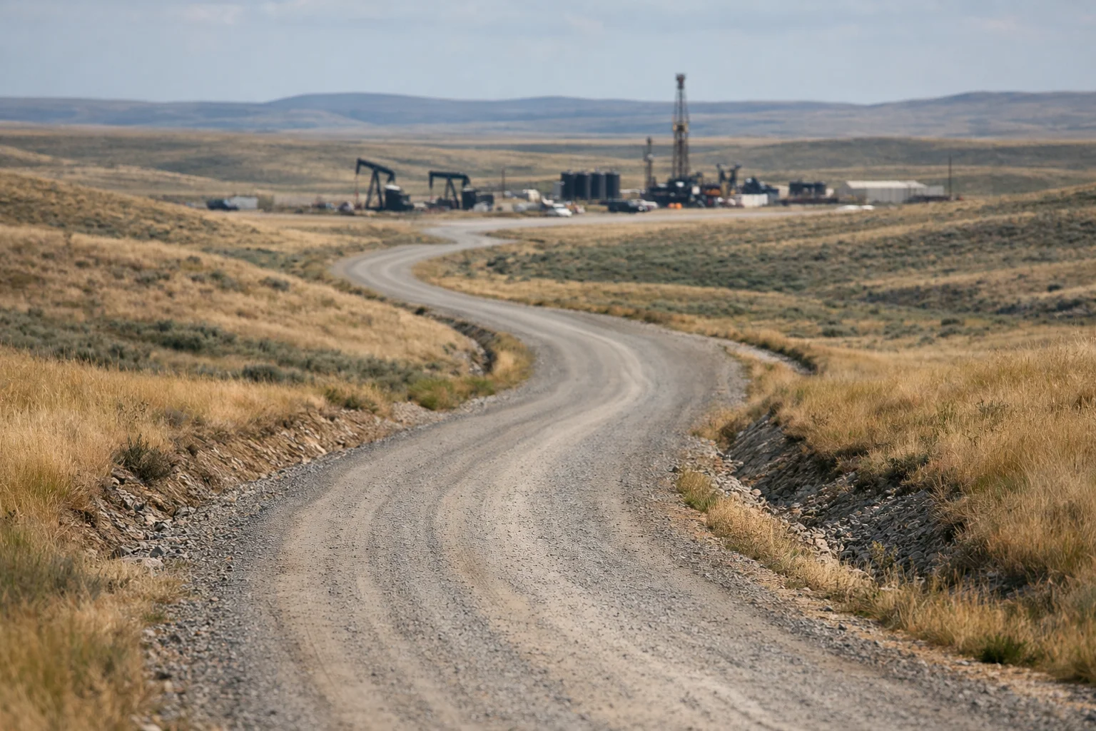 Well-maintained gravel access road through rangeland