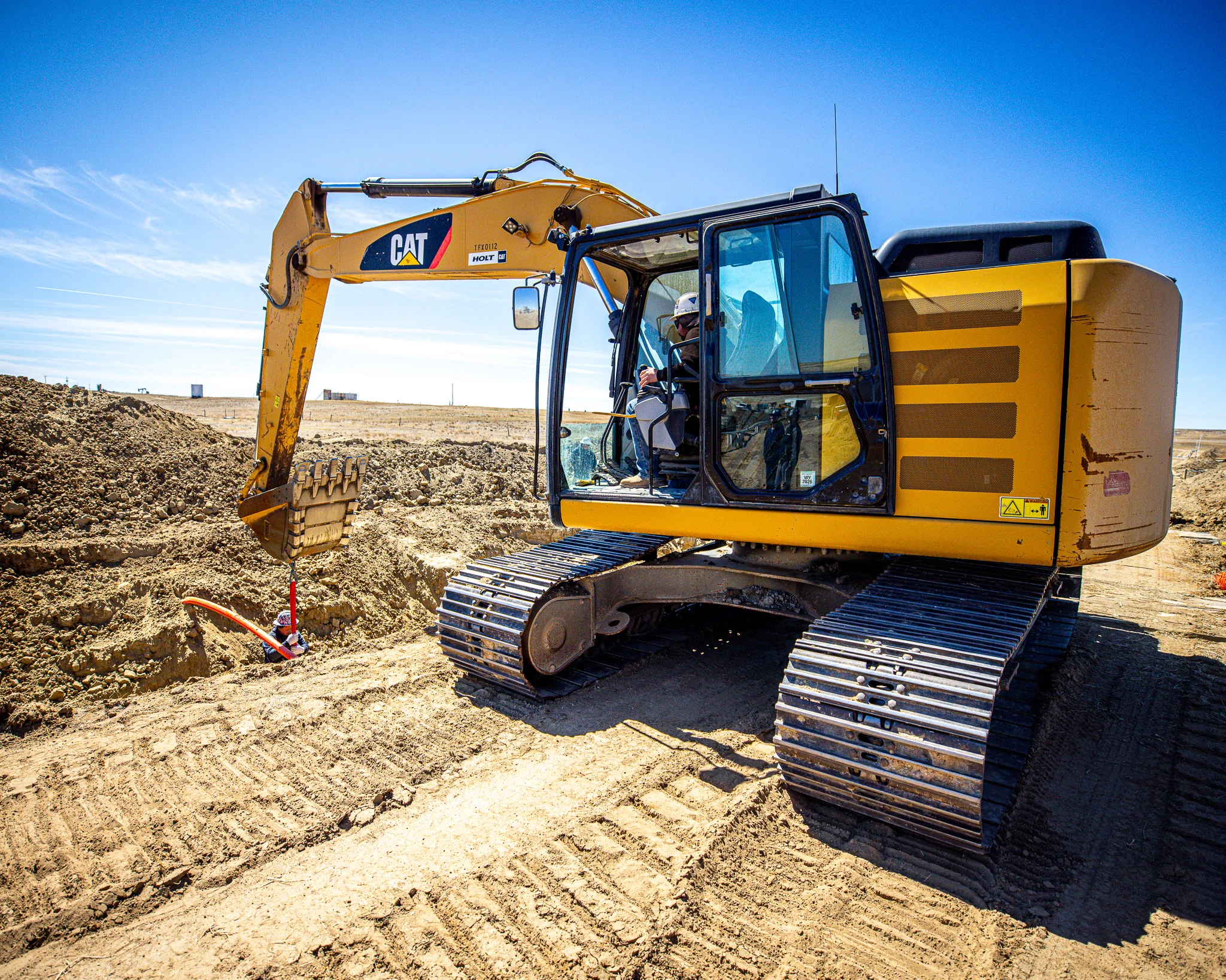 CAT excavator working at pipeline trench on a WYO Services job site
