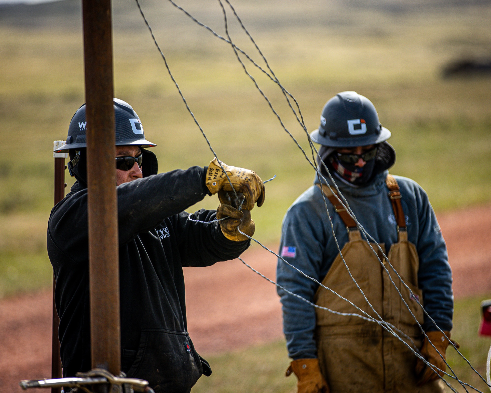 WYO Services crew stringing barbed wire on oilfield fence line