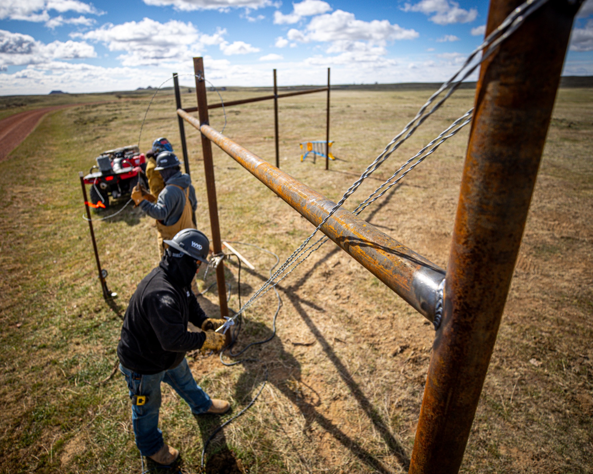 WYO Services crew tensioning wire on pipe fence line in Wyoming