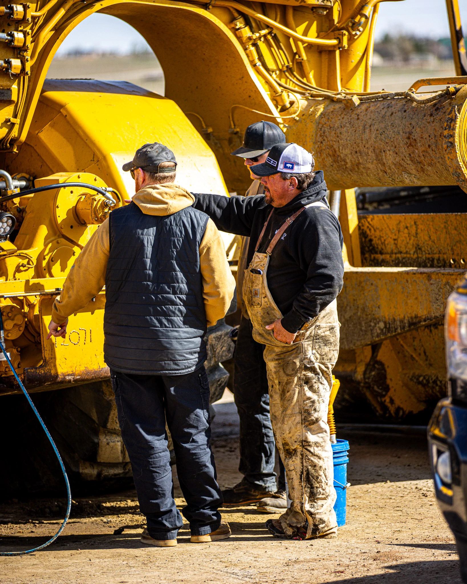 WYO Services crew members discussing work beside heavy equipment